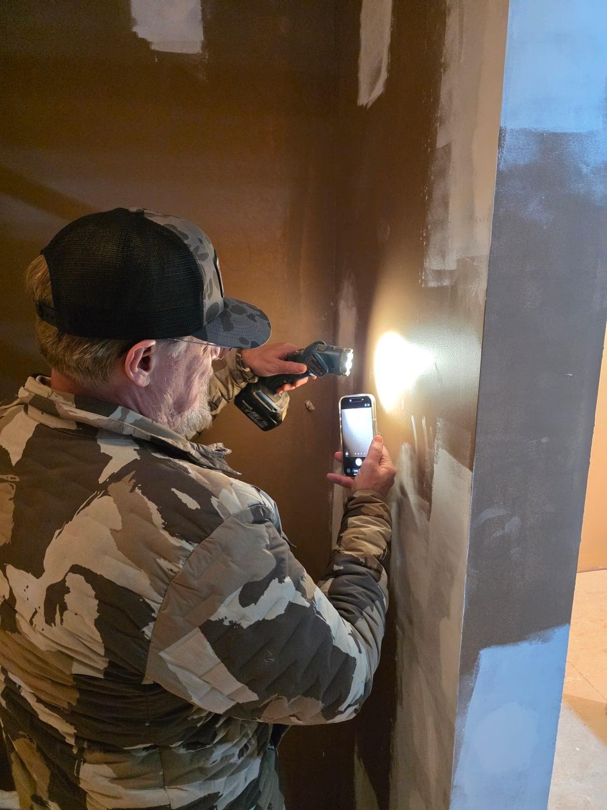 Mission Painting crew member using a high-intensity pan light to inspect painted surfaces for imperfections